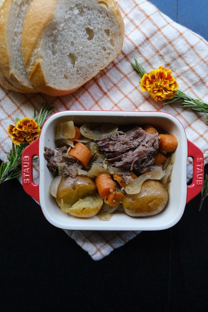 photo of the perfect pot roast plated on a counter top next to bread