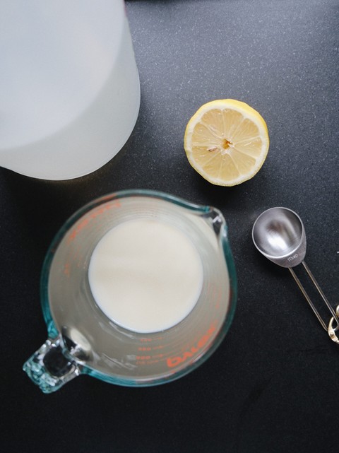 flat lay photo of buttermilk substitute ingredients featuring lemon, milk, measuring spoon, and vinegar