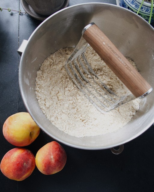 mixing bowl with flour and peaches next to bowl