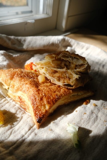 open faced apple pie turnovers with puff pastry laying on towel in sunlight