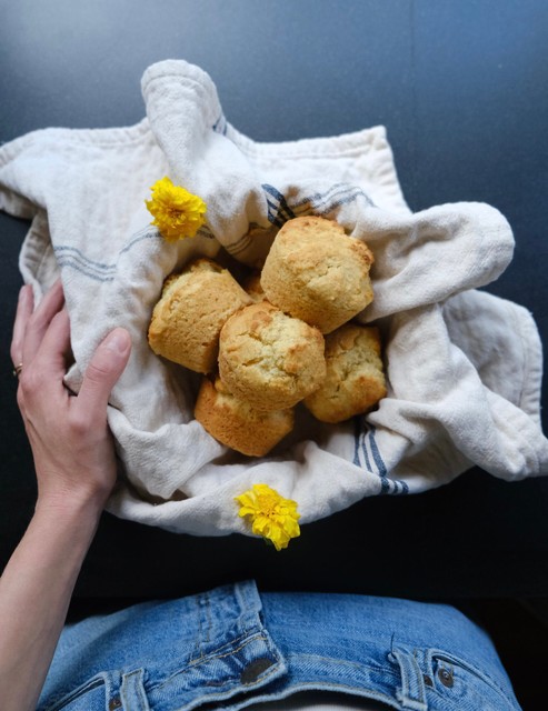hand holding bowl of cornbread muffins with two yellow flowers